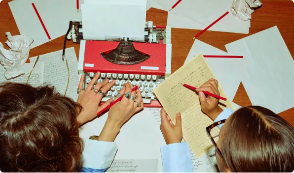 People hovering over a copywriter on a cluttered desk