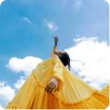 Woman in yellow dress pointing up at the sky.