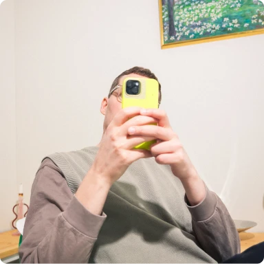 Person in grey shirt holding up a yellow mobile in front of his face.