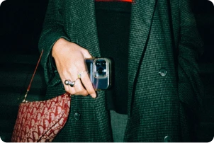 Woman dressed in black holding her phone.
