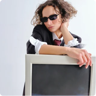 Femail in sunglasses and suit hovering over a computer screen.
