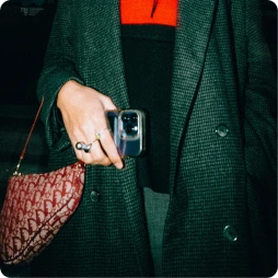 Woman dressed in a black jacket holding a phone in her hand.